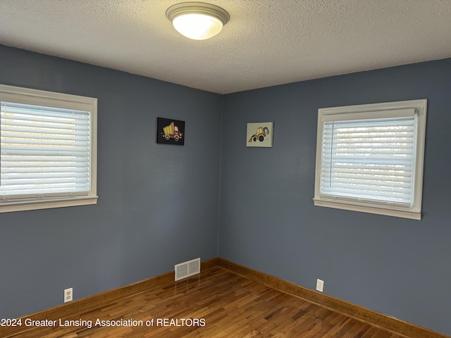 empty room with wood-type flooring and a textured ceiling