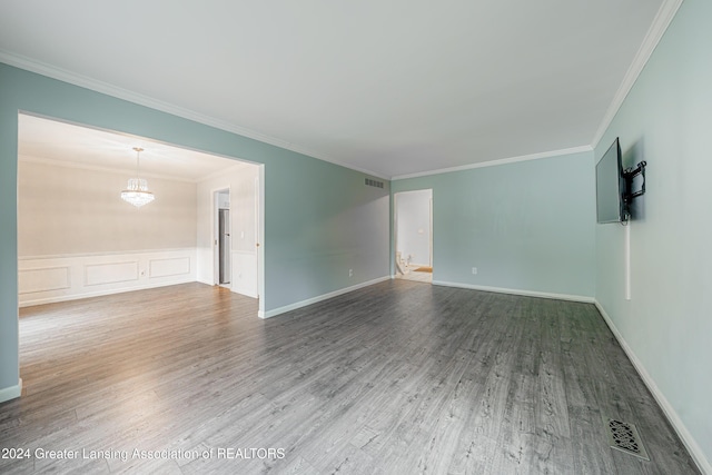 unfurnished room featuring hardwood / wood-style flooring, an inviting chandelier, and crown molding