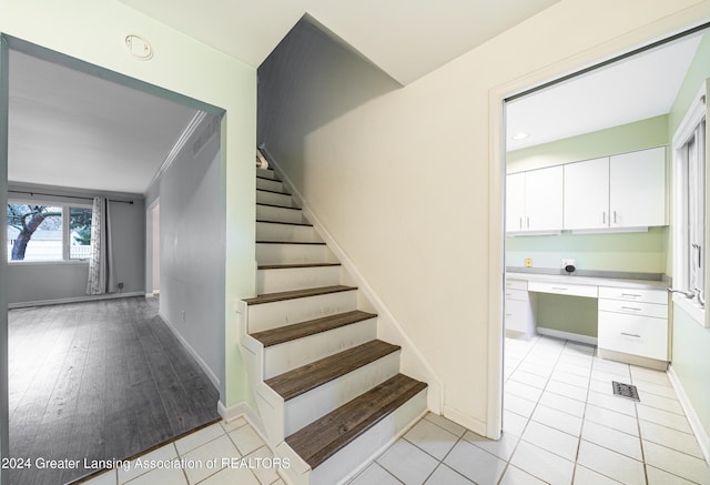 stairs with built in desk, tile patterned flooring, and ornamental molding