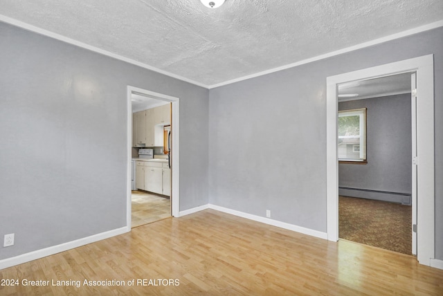 empty room with ornamental molding, light hardwood / wood-style flooring, a textured ceiling, and a baseboard heating unit