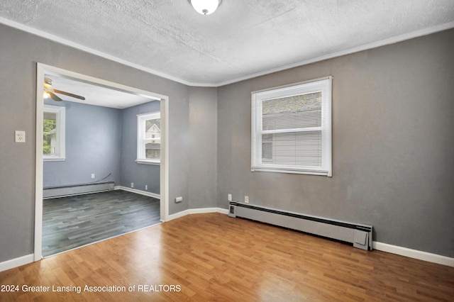 unfurnished room with a textured ceiling, a baseboard heating unit, hardwood / wood-style floors, and ceiling fan