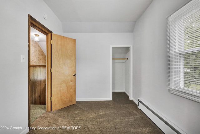 unfurnished bedroom featuring a closet, a baseboard radiator, lofted ceiling, and dark carpet