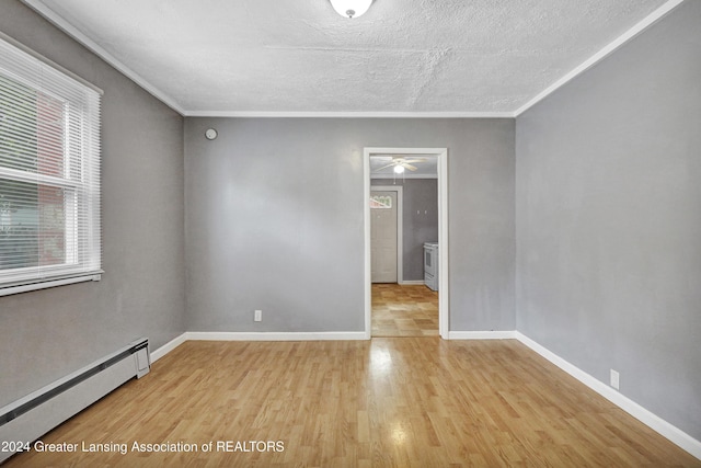 unfurnished room featuring crown molding, baseboard heating, ceiling fan, and light wood-type flooring