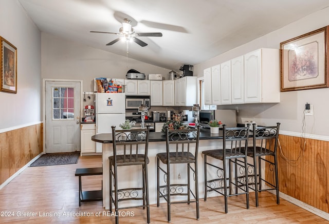 kitchen with a kitchen breakfast bar, vaulted ceiling, light wood-type flooring, kitchen peninsula, and white cabinetry