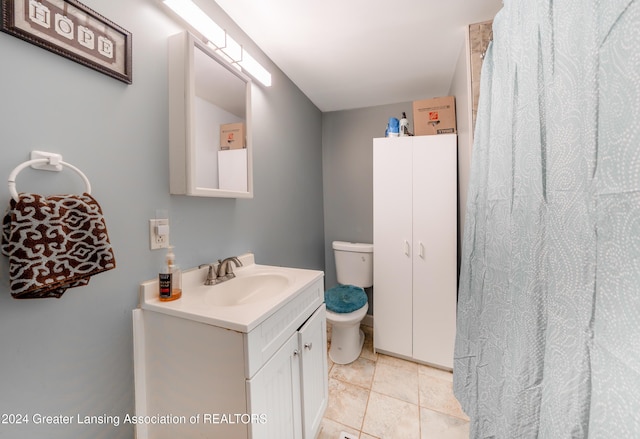 bathroom with toilet, vanity, and tile patterned flooring