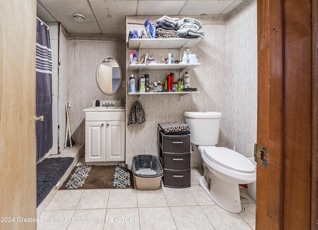 bathroom featuring toilet, tile patterned flooring, a drop ceiling, and vanity