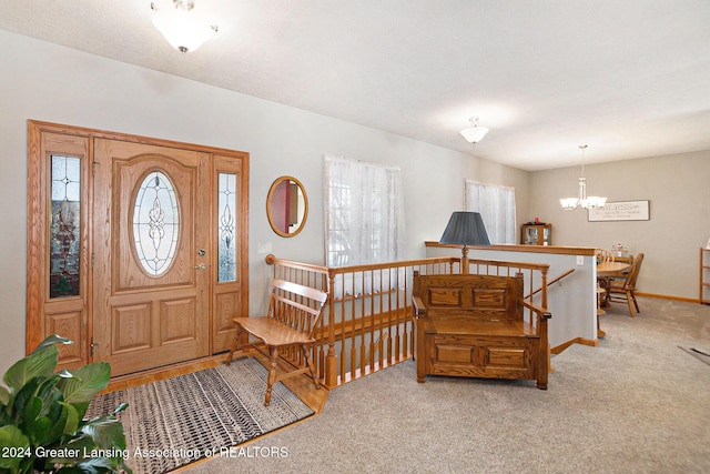 foyer entrance with light colored carpet and an inviting chandelier