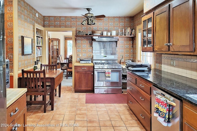 kitchen with extractor fan, stainless steel appliances, light tile patterned floors, dark stone counters, and ceiling fan