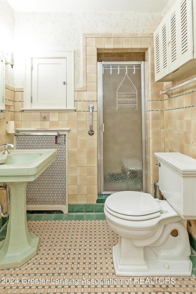 bathroom featuring toilet, an enclosed shower, and tile walls