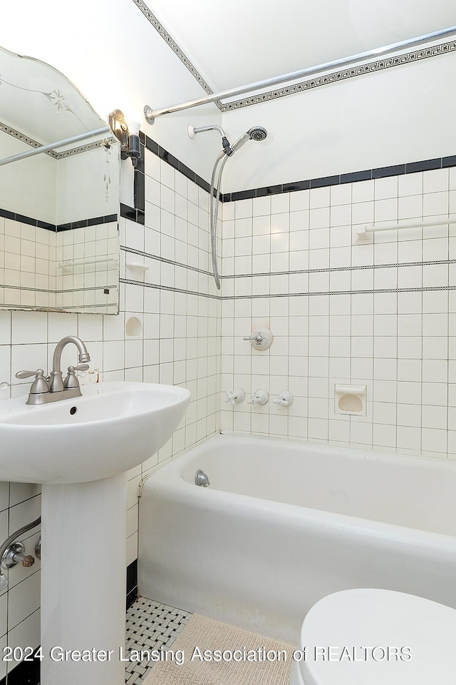 bathroom with tile patterned flooring, backsplash, tiled shower / bath combo, and toilet