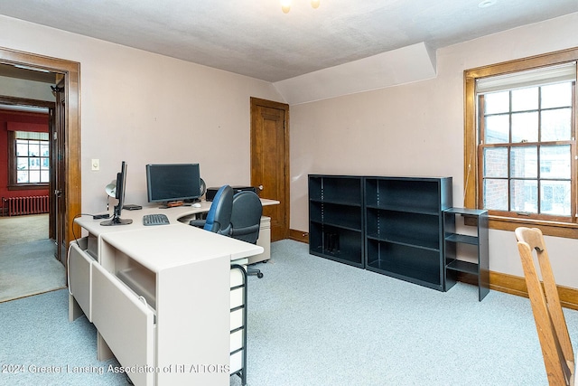 office area featuring light carpet, radiator heating unit, and vaulted ceiling