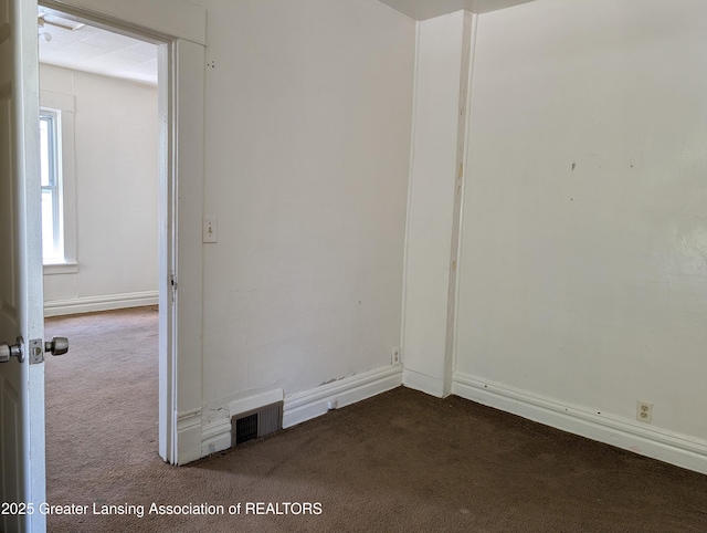 unfurnished room with dark colored carpet, baseboards, and visible vents
