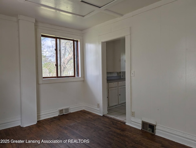 empty room with baseboards, dark wood finished floors, attic access, and visible vents
