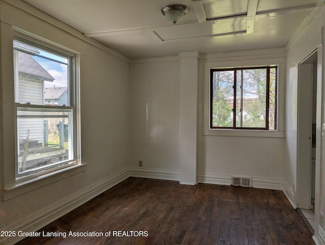 unfurnished room with a wealth of natural light, dark wood finished floors, and visible vents