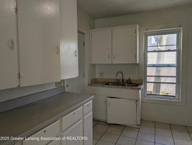 kitchen with light countertops, white cabinetry, light tile patterned floors, and a sink