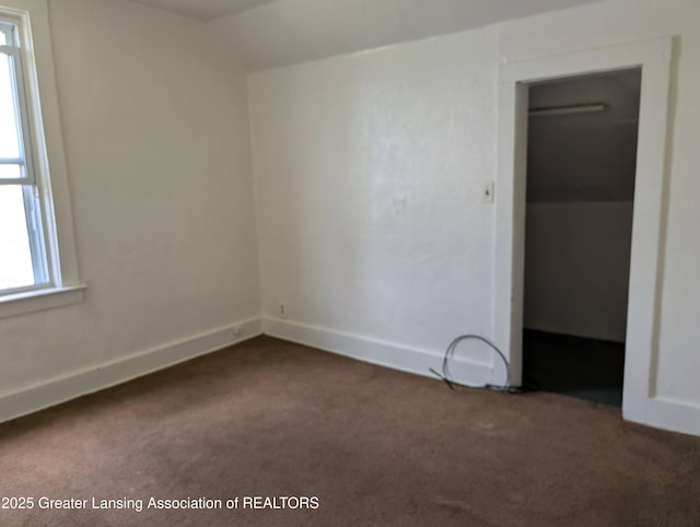 unfurnished bedroom with carpet flooring, multiple windows, baseboards, and lofted ceiling