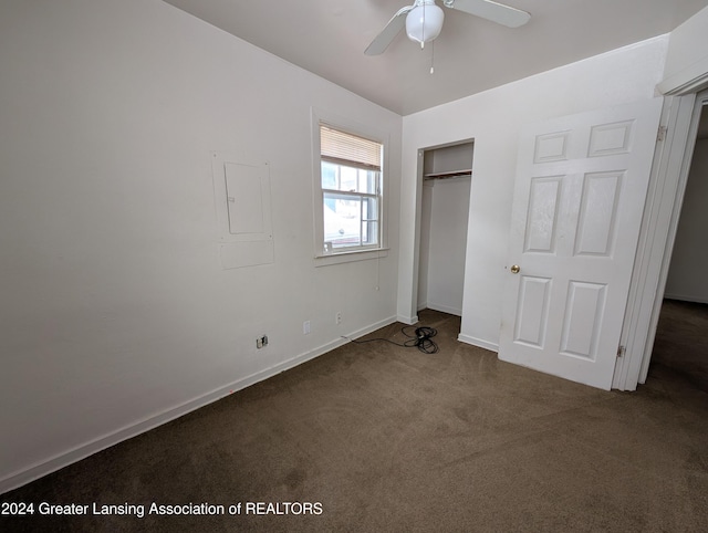 unfurnished bedroom featuring ceiling fan, electric panel, a closet, and dark colored carpet