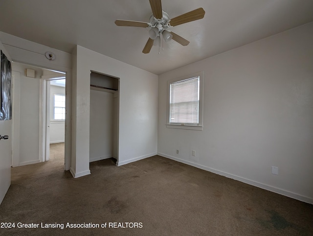 unfurnished bedroom featuring ceiling fan, a closet, and dark colored carpet