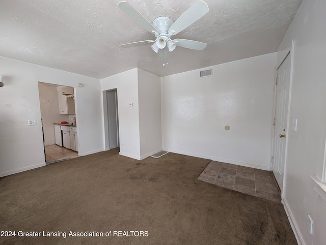 empty room with light carpet, ceiling fan, and a textured ceiling