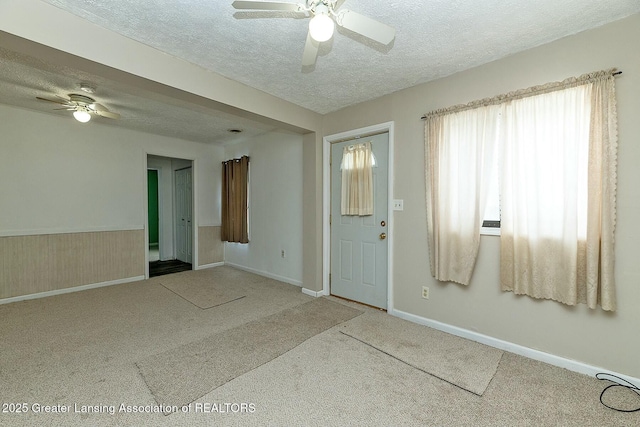 carpeted spare room featuring ceiling fan, wooden walls, and a textured ceiling