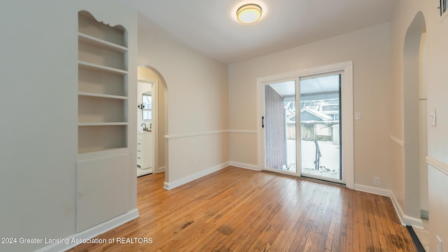 empty room featuring built in features and light hardwood / wood-style floors