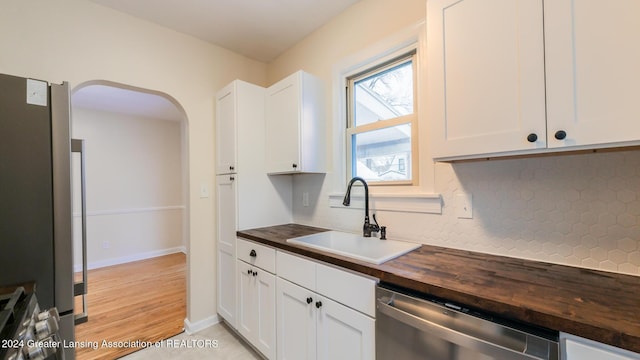 kitchen with sink, white cabinets, dishwasher, and wooden counters