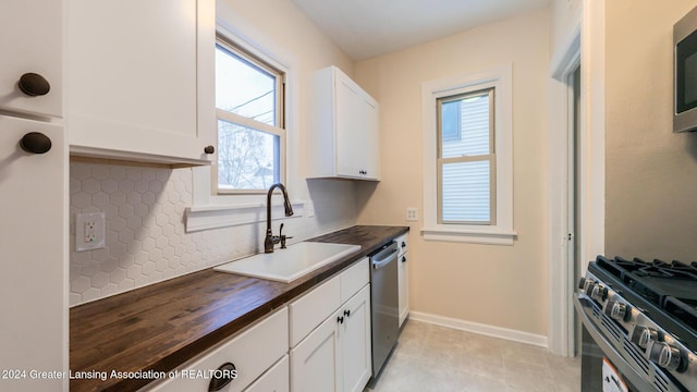 kitchen featuring stainless steel appliances, white cabinets, wooden counters, and sink