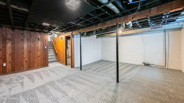 basement featuring carpet and wooden walls