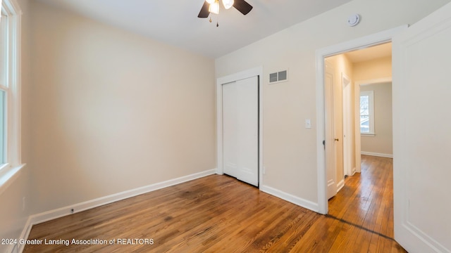 unfurnished bedroom with ceiling fan, a closet, and hardwood / wood-style floors