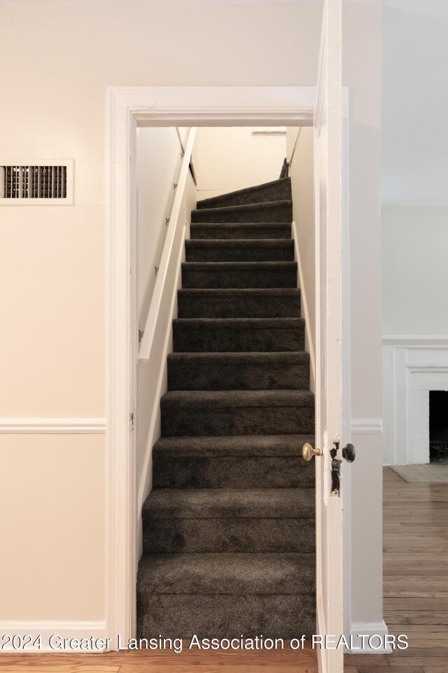 stairway featuring hardwood / wood-style flooring and a fireplace