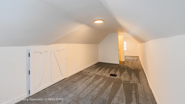 additional living space with vaulted ceiling and dark colored carpet