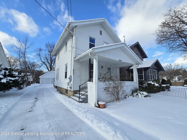 view of snowy exterior featuring a garage and an outbuilding