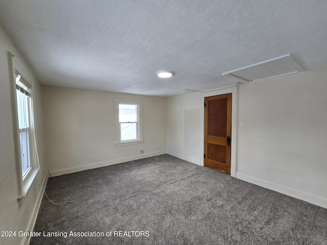 unfurnished room with dark carpet and a textured ceiling