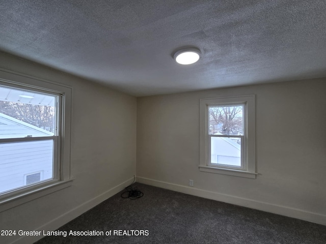 unfurnished room featuring dark colored carpet