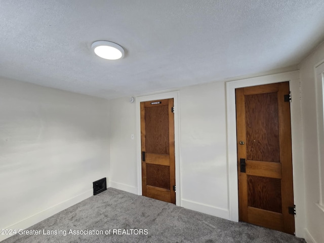 unfurnished room with a textured ceiling and carpet flooring