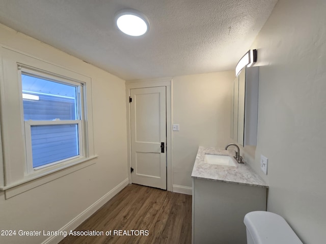 bathroom featuring toilet, vanity, a textured ceiling, and hardwood / wood-style floors