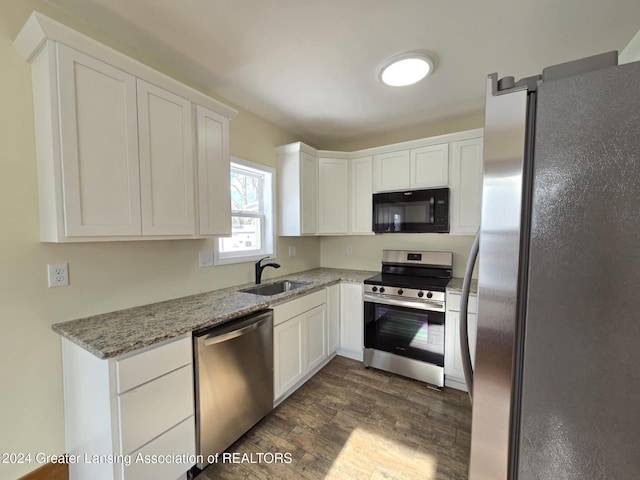 kitchen with light stone countertops, white cabinets, dark hardwood / wood-style flooring, stainless steel appliances, and sink