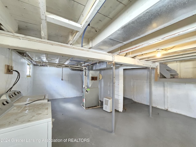 basement featuring heating unit and washer and clothes dryer