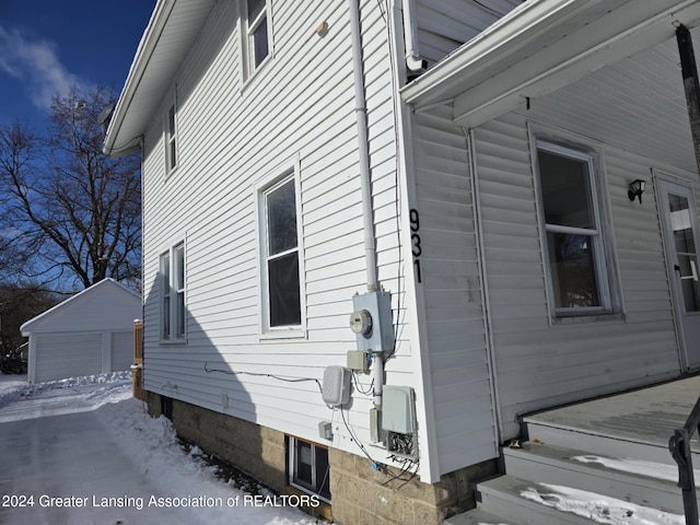 snow covered property with an outbuilding and a garage