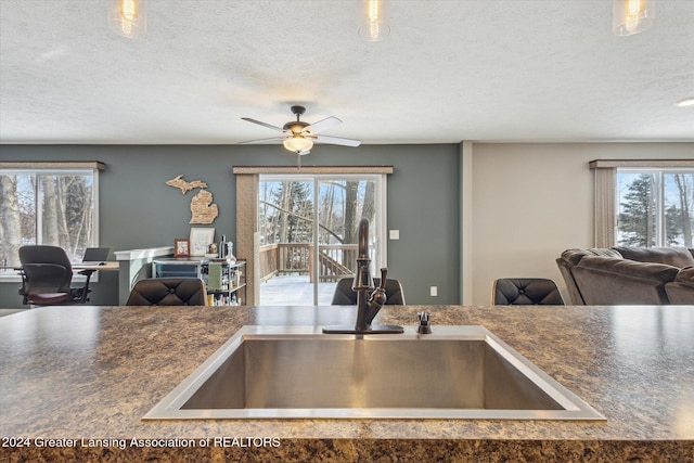 kitchen with a textured ceiling, ceiling fan, a wealth of natural light, and sink