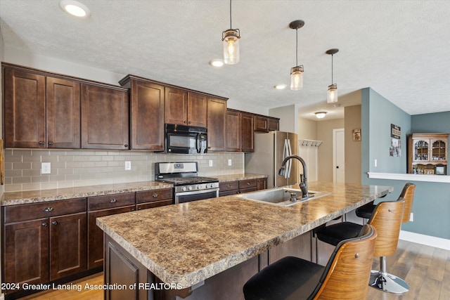 kitchen with backsplash, dark hardwood / wood-style floors, sink, a breakfast bar area, and stainless steel appliances