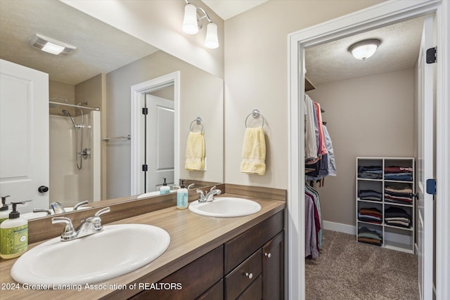 bathroom featuring a textured ceiling, walk in shower, and vanity