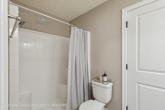 bathroom with a textured ceiling, toilet, and a shower with curtain