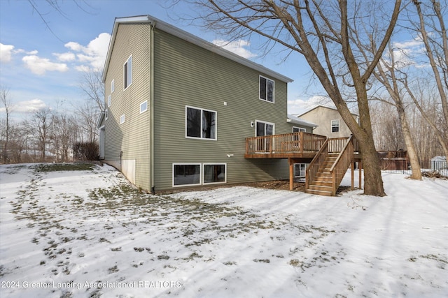 snow covered back of property with a deck