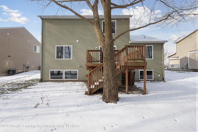 snow covered rear of property featuring a wooden deck and cooling unit