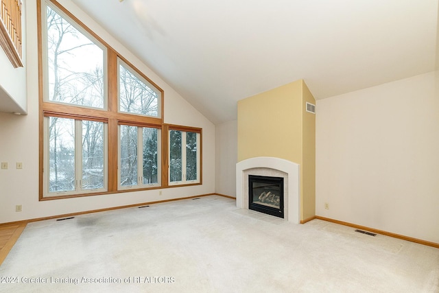 unfurnished living room with a high ceiling, light colored carpet, and a healthy amount of sunlight