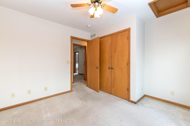 unfurnished bedroom featuring ceiling fan, light colored carpet, and a closet