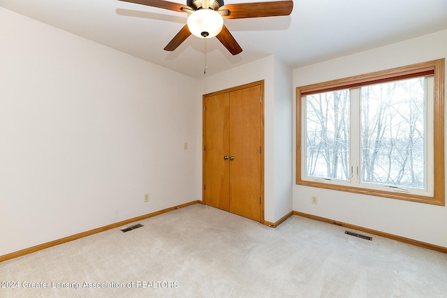 unfurnished bedroom featuring a closet, ceiling fan, and light carpet