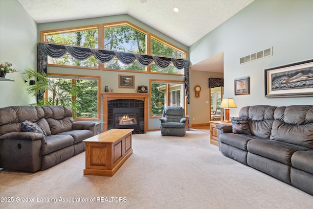 living room with high vaulted ceiling, light carpet, a tile fireplace, and a textured ceiling