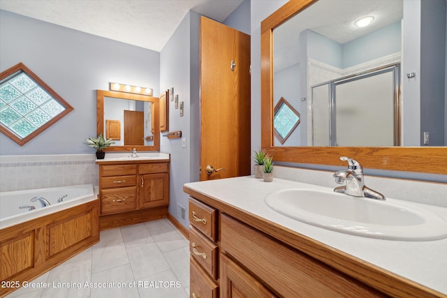 bathroom featuring tile patterned flooring, vanity, independent shower and bath, and a textured ceiling